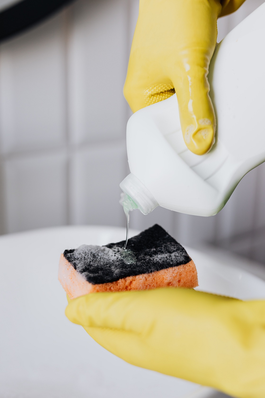 keep on cleaning and maid services pooring soap on a sponge with gloves