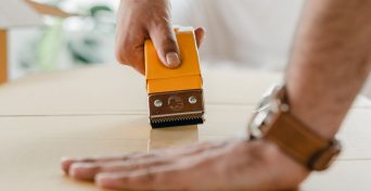 crop-man-using-scotch-tape-dispenser-for-packing-carton-box-4246094